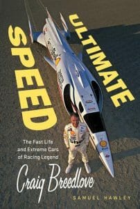 Book cover with a man in a racing suit beside a sleek silver land speed car on desert flats. Title: “Ultimate Speed: Craig Breedlove” by Samuel Hawley.