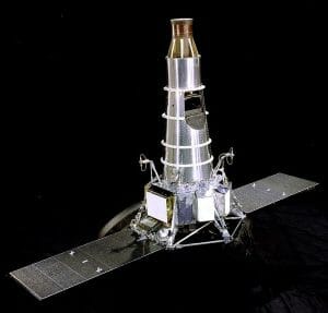 A metallic space probe with a conical body, antenna, and two rectangular solar panels extends outward on a black background.