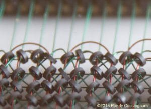 Close-up view of a vintage wire and ferrite core memory array, showing green and red wires threaded through circular black cores. ©2018 Randy Cassingham is noted in the corner.
