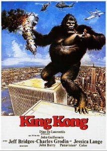 A giant gorilla stands atop a skyscraper, swatting at helicopters and holding a damaged plane as city buildings stretch below; “King Kong” is written in bold red text with credits beneath.