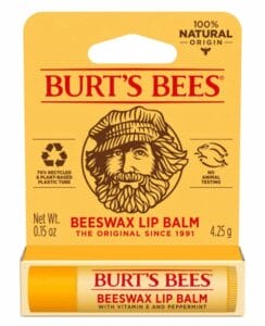 A package of Burt’s Bees Beeswax Lip Balm featuring a drawing of a bearded man, text highlighting natural origin ingredients, recyclable packaging, and no animal testing. The lip balm tube is visible at the bottom.
