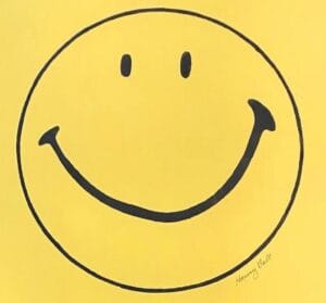 A simple yellow background with a large black-outlined smiley face featuring two oval eyes and a curved smile. The image is signed Harvey Ball in the lower right corner.