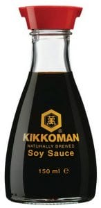 A glass bottle of Kikkoman naturally brewed soy sauce with a red plastic cap. The label features the Kikkoman logo and gold text on the front.