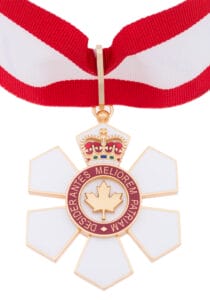 A medal with a red and white ribbon, a crown at the top, and a white six-pointed flower with a red ring that reads Desiderantes Meliorem Patriam, featuring a maple leaf in the center.