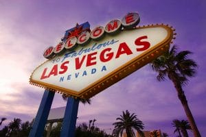 Iconic Welcome to Fabulous Las Vegas, Nevada sign, lit up against a purple sky at dusk, surrounded by palm trees.